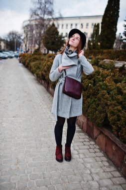 Genç kız bir gri ceket ve deri handb ile siyah şapka modeli