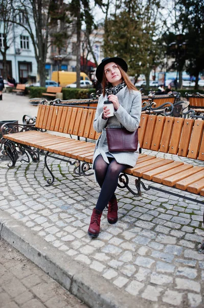Chica modelo joven en un abrigo gris y sombrero negro con la mano de cuero — Foto de Stock