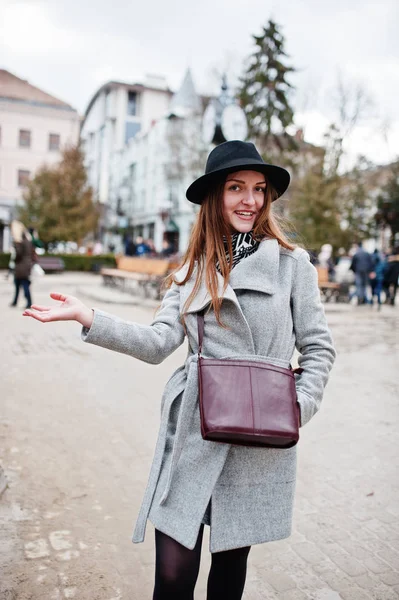 Junges Model-Mädchen in grauem Mantel und schwarzem Hut mit Lederhandgriff — Stockfoto