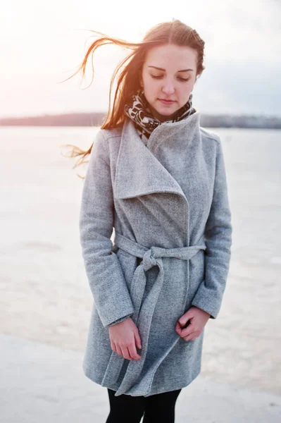Jeune fille modèle en manteau gris avec des cheveux rouges contre le gel du lac . — Photo