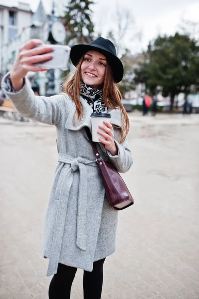 Junges Model-Mädchen in grauem Mantel und schwarzem Hut mit Lederhandgriff — Stockfoto