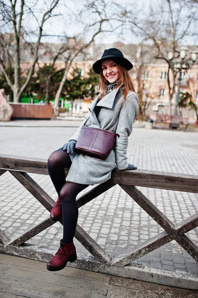 Junges Model Mädchen in grauem Mantel und schwarzem Hut mit Lederhandtasche — Stockfoto