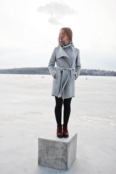 Jeune fille modèle en manteau gris posé sur le cube de pierre contre le gel — Photo