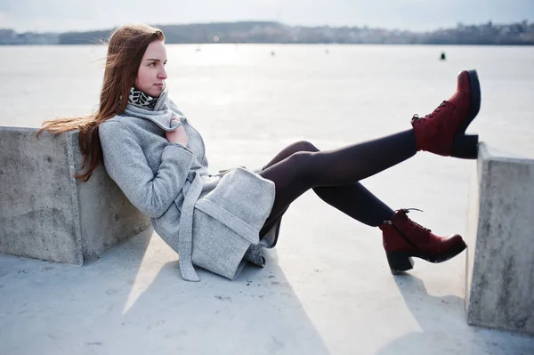 Jovem modelo menina em casaco cinza posou sentado perto de pedra cubo agai — Fotografia de Stock