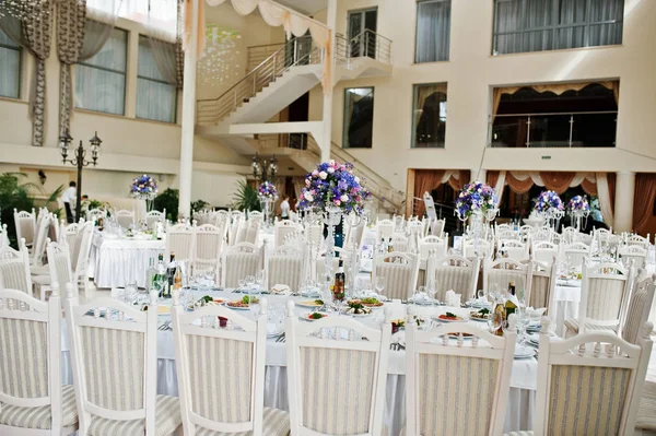 Αίθουσα του φοβερό γάμου με λευκές καρέκλες και μοβ λουλούδια σε καρτέλα — Φωτογραφία Αρχείου