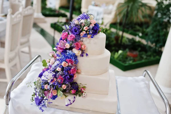 Wedding cake with purple and violet flowers at hall. — Stock Photo, Image