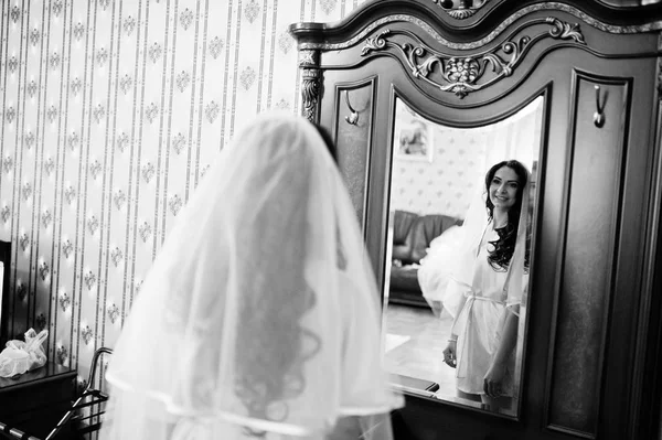 Brunetki Panna Młoda w szlafrok, patrząc w lustro na pokój w hotelu — Zdjęcie stockowe
