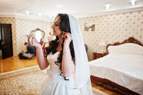 결혼식 아침에 호텔 방에 귀걸이 착용 하는 신부. — 스톡 사진