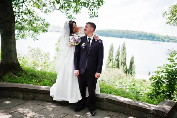 Liebendes Hochzeitspaar umarmt Hintergrundlandschaft mit See. — Stockfoto