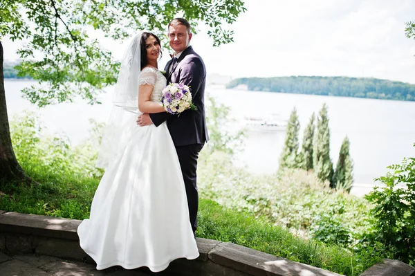 Liebendes Hochzeitspaar umarmt Hintergrundlandschaft mit See. — Stockfoto