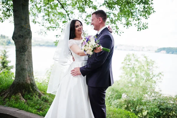 Loving wedding couple hugging backgroun landscape with lake. — Stock Photo, Image