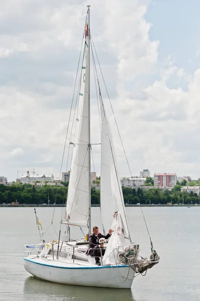 Casamento casal apaixonado em pequeno iate veleiro no lago . — Fotografia de Stock