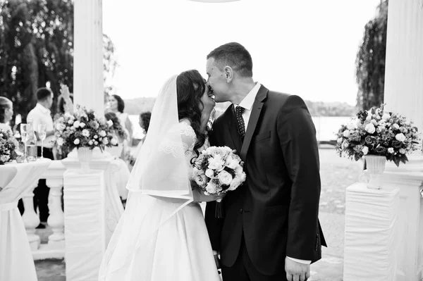 Casamento casal beijou sob arco branco na cerimônia de casamento. Lâmina — Fotografia de Stock