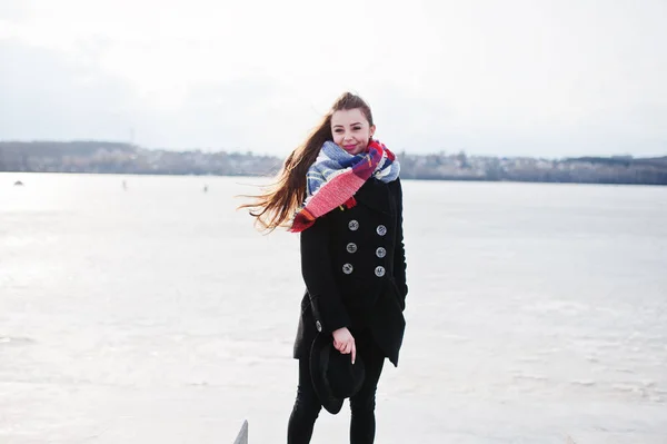 Casual jeune fille à manteau noir, écharpe et chapeau contre ri congelé — Photo