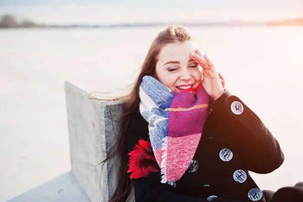 Casual young girl at black coat, scarf and hat against frozen ri — Stock Photo, Image