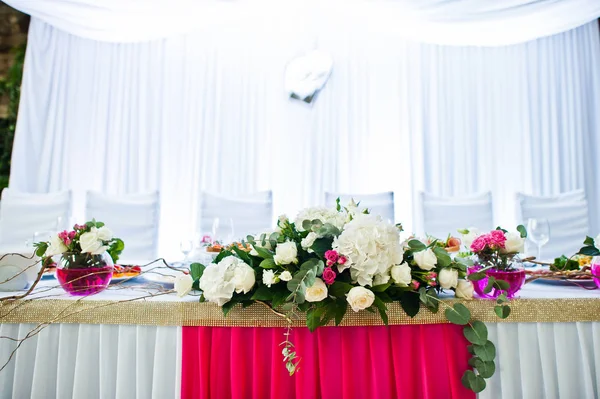 Flowers on vase with pink water at table of newlyweds. — Stock Photo, Image