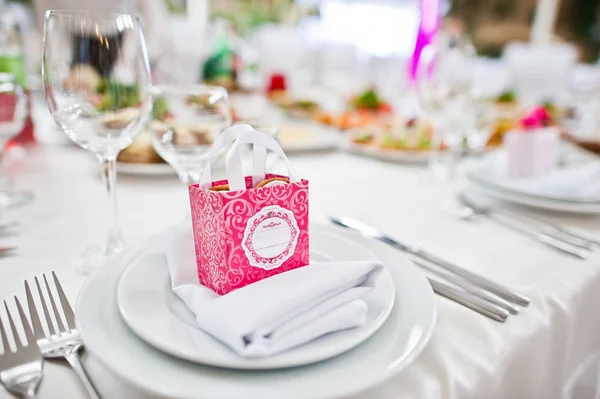 Kleine rosa Schachtel mit Bonbons am Tisch auf dem Teller des Hochzeitsgastes. — Stockfoto