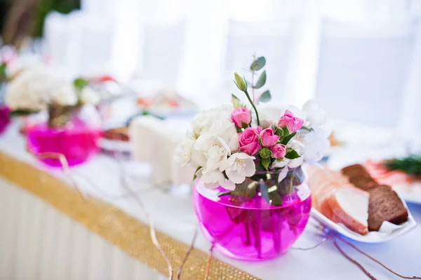 Yeni evliler, masada pembe su ile vazo çiçekleri. — Stok fotoğraf