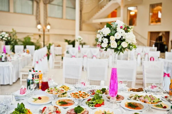 Blommor på vas med rosa vatten vid bordet av bröllopsgäster. — Stockfoto