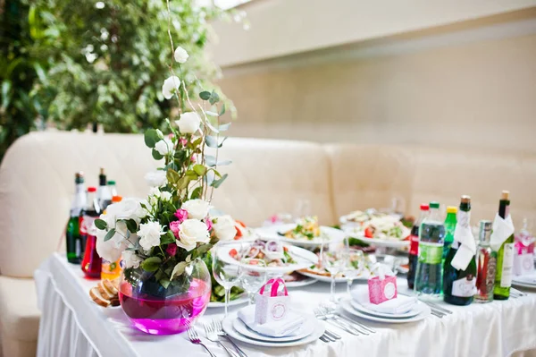 Fiori su vaso con acqua rosa a tavola di ospiti nuziali . — Foto Stock