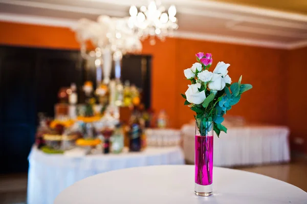 Blommor på vas med rosa vatten vid bordet av bröllopsgäster. — Stockfoto