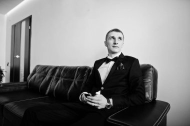 Deri koltukta oturan genç şık damat. Siyah ve beyaz pho
