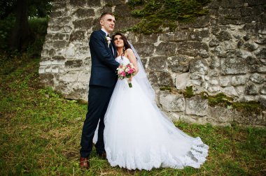 Genç şık Düğün çifti eski taş duvara.