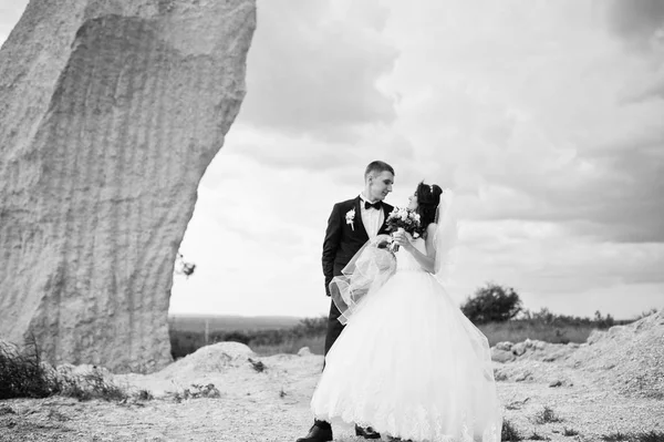 Joven pareja de boda con estilo contra la carrera arenosa en el cielo nublado . —  Fotos de Stock