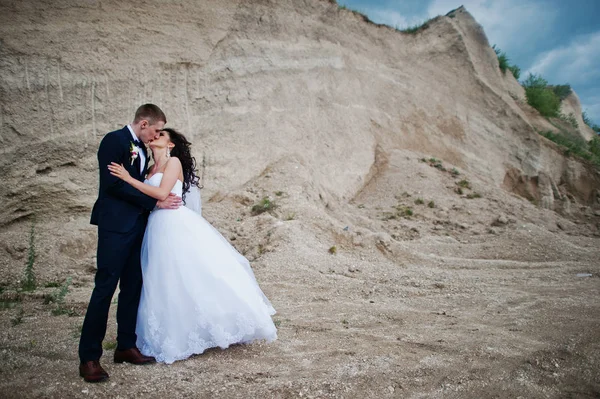 Νέοι Κομψό γαμήλιο ζεύγος εναντίον αμμώδη καριέρα στο συννεφιασμένο ουρανό. — Φωτογραφία Αρχείου