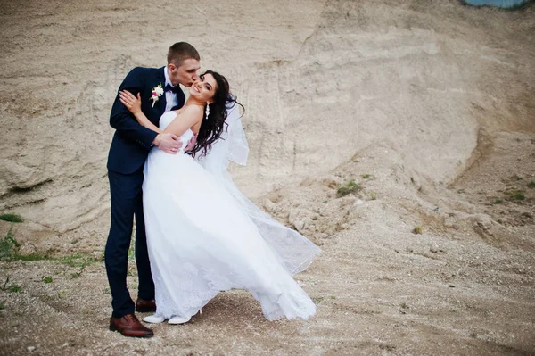 Ung snygg bröllopsparet mot sandstranden karriär på mulen himmel. — Stockfoto