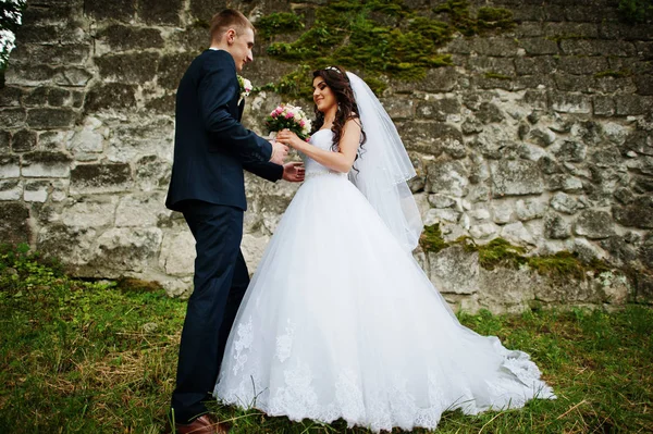 年轻时尚的婚礼夫妇老石头墙. — 图库照片