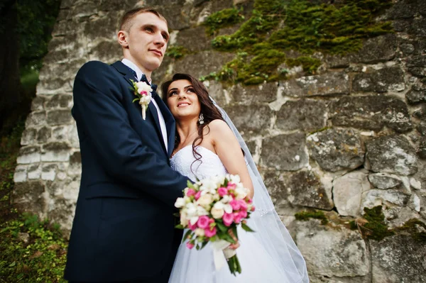 Jeune couple de mariage élégant contre vieux mur de pierre . — Photo