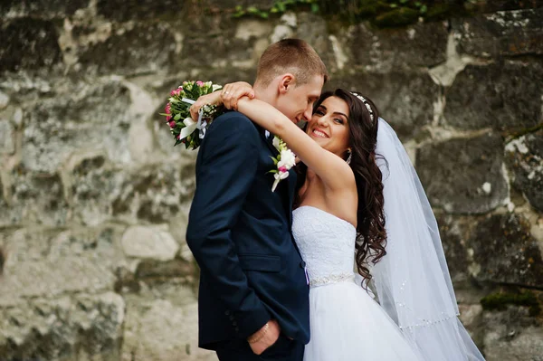 Casal de casamento elegante jovem contra parede de pedra velha . — Fotografia de Stock