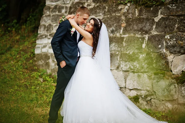 Joven pareja de boda con estilo contra la pared de piedra vieja . — Foto de Stock