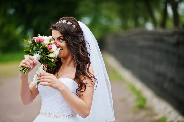 Okouzlující brunetka nevěsty s kyticí v parku. — Stock fotografie