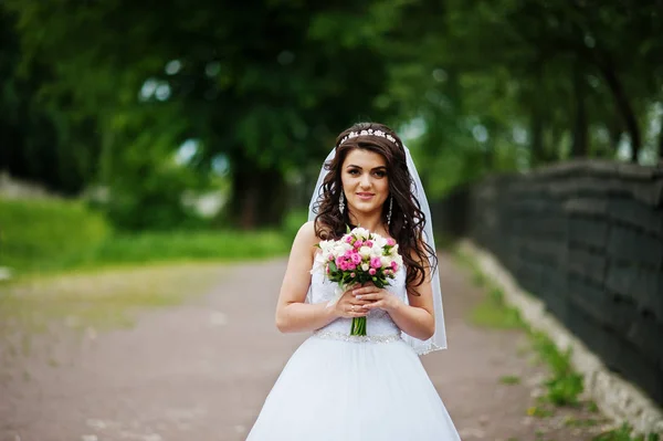 Очаровательная брюнетка невеста с букетом в парке . — стоковое фото