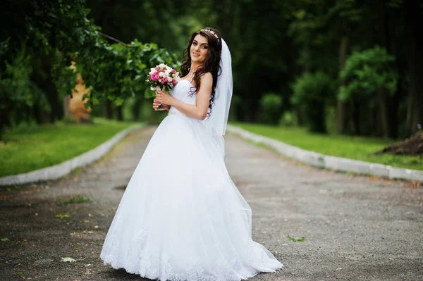 Charming brunette bride with bouquet at park. — Stock Photo, Image
