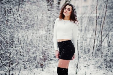 Kıvırcık esmer kız arka plan yağan kar, siyah mini aşınma 