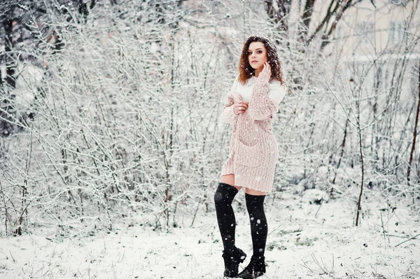 Lockige brünette Mädchen Hintergrund fallenden Schnee, tragen auf warmen Strick — Stockfoto