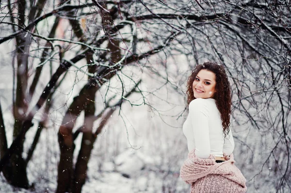 Lockig brunett flicka bakgrund faller snö, slitage på varma sticka — Stockfoto