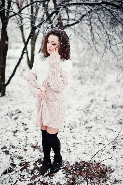Lockig brunett flicka bakgrund faller snö, slitage på varma sticka — Stockfoto