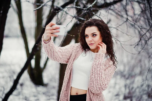 Menina morena encaracolado com telefone celular na mão fazendo selfie de volta — Fotografia de Stock