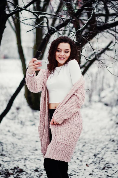 Lockiges brünettes Mädchen mit Handy in der Hand macht Selfie zurück — Stockfoto