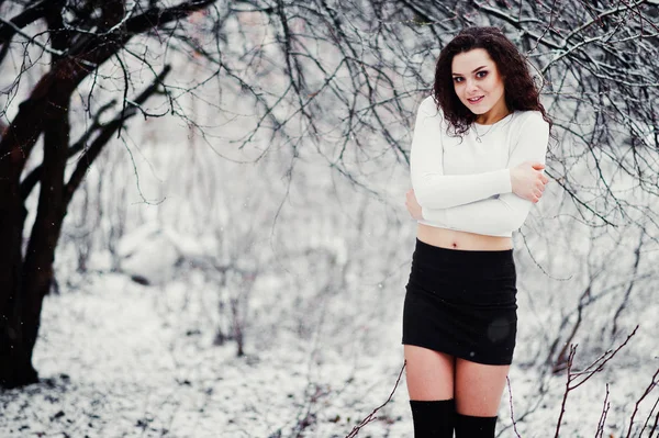 Curly brunette girl background falling snow, wear on black mini — Stock Photo, Image