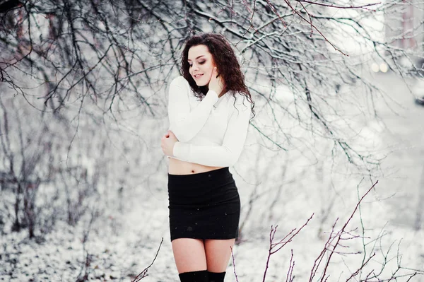 Curly brunette girl background falling snow, wear on black mini — Stock Photo, Image