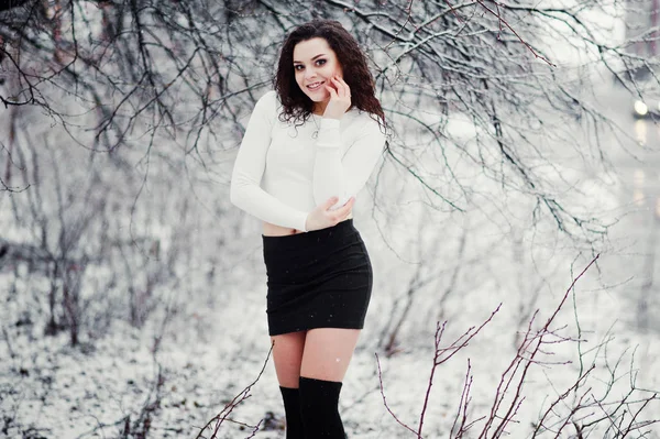Rizado chica morena fondo cayendo nieve, desgaste en negro mini — Foto de Stock