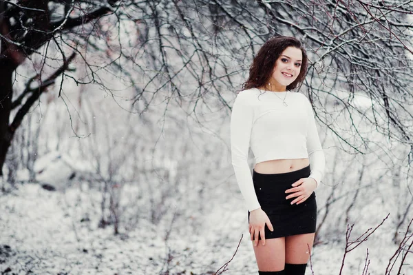 カーリー ブルネットの少女背景雪、黒いミニの摩耗 — ストック写真