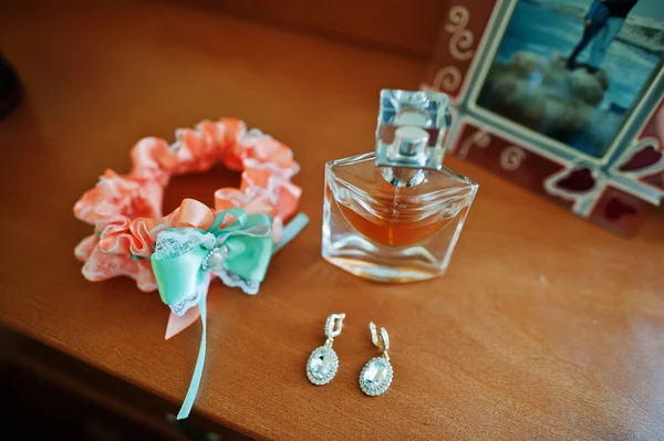 Jarretière de mariée orange et verte avec boucles d'oreilles et parfum à table — Photo