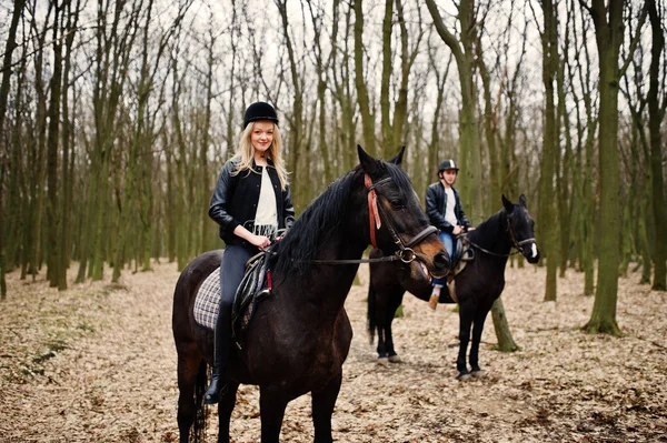 Ung snygg par ridning på hästar på hösten skogen. — Stockfoto