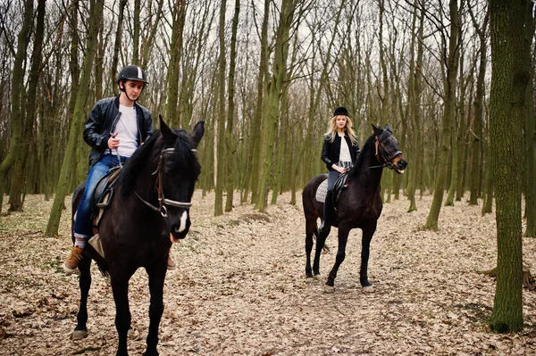 Jong stijlvolle koppel rijden op paarden op herfst bos. — Stockfoto